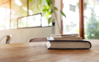 Books and notebooks on a wooden table illustrating the Cambridge ERA:AI Fellowship Summer 2026